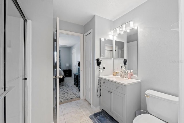 ensuite bathroom with connected bathroom, toilet, tile patterned flooring, an enclosed shower, and vanity