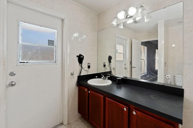 bathroom with a wealth of natural light, vanity, tile walls, and tile patterned floors