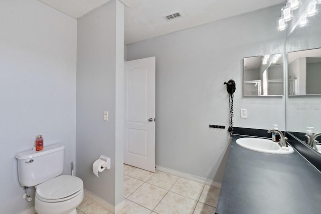 bathroom featuring tile patterned flooring, toilet, vanity, visible vents, and baseboards