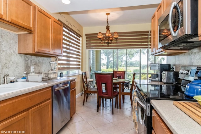 kitchen with light tile patterned floors, a notable chandelier, light countertops, appliances with stainless steel finishes, and decorative backsplash