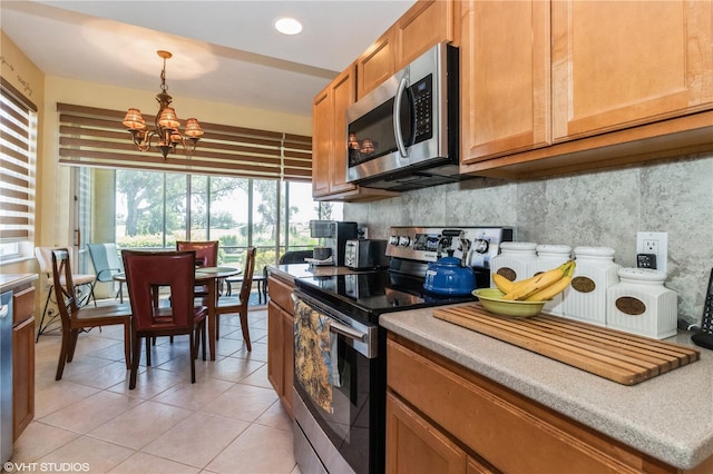 kitchen with a chandelier, light tile patterned flooring, appliances with stainless steel finishes, tasteful backsplash, and pendant lighting