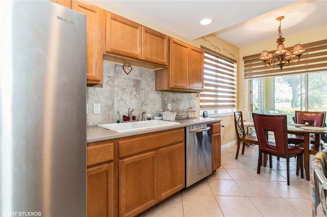 kitchen with decorative backsplash, appliances with stainless steel finishes, light countertops, a sink, and light tile patterned flooring