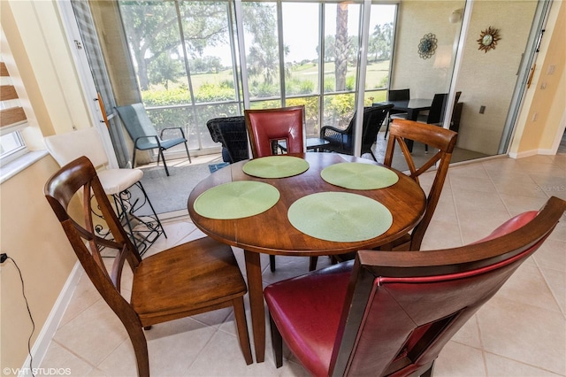 tiled dining area featuring a sunroom and baseboards