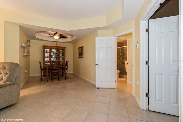 dining space featuring baseboards, a raised ceiling, a ceiling fan, and light tile patterned flooring