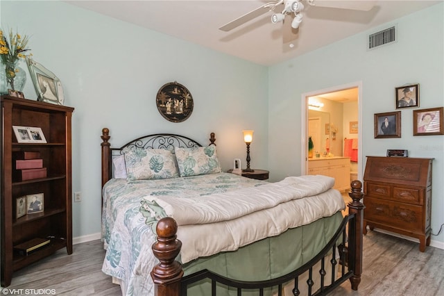 bedroom with ensuite bath, wood finished floors, visible vents, and baseboards