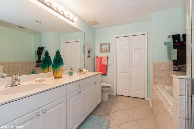 bathroom featuring a relaxing tiled tub, tile patterned flooring, a sink, and visible vents