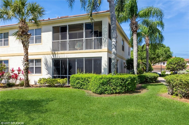 back of property with a lawn and stucco siding