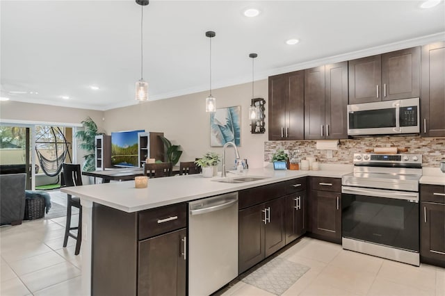 kitchen with a peninsula, appliances with stainless steel finishes, light countertops, and a sink