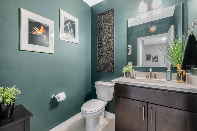 half bathroom with baseboards, vanity, toilet, and tile patterned floors