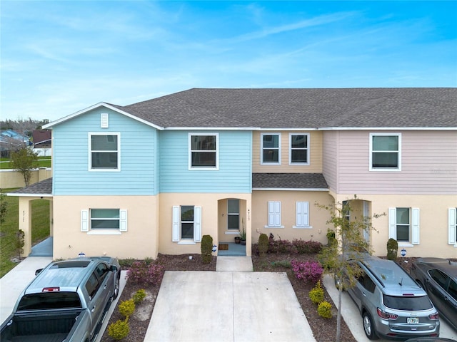 multi unit property with a shingled roof and stucco siding