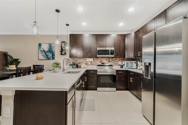 kitchen with tasteful backsplash, appliances with stainless steel finishes, a sink, dark brown cabinetry, and a peninsula