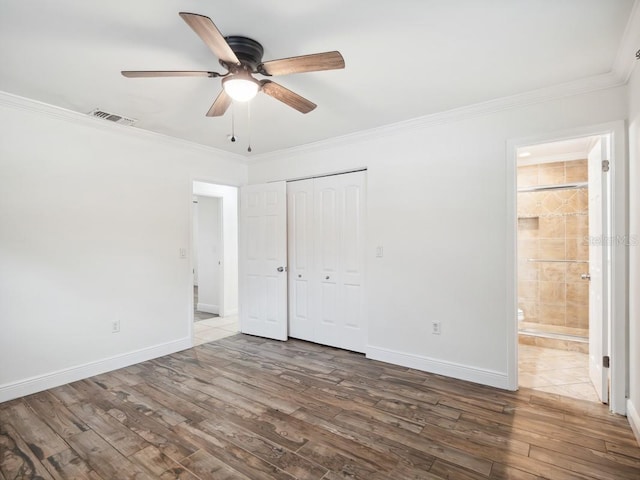 unfurnished bedroom with baseboards, crown molding, visible vents, and wood finished floors