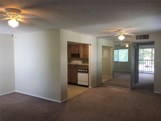 kitchen with light carpet, brown cabinetry, a sink, and visible vents