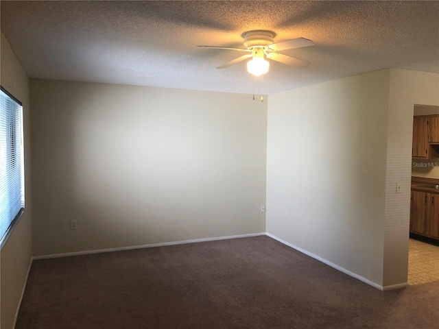 carpeted spare room featuring ceiling fan, a textured ceiling, and baseboards