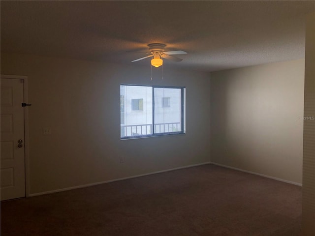carpeted spare room featuring a textured ceiling, baseboards, and a ceiling fan