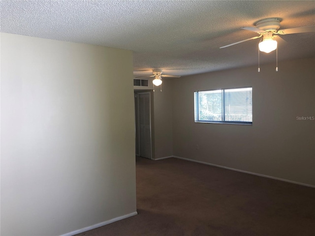 empty room featuring a textured ceiling, ceiling fan, visible vents, baseboards, and dark colored carpet