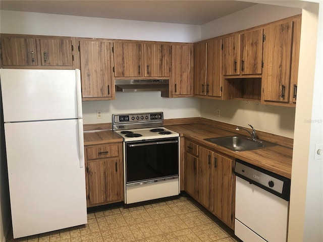kitchen with white appliances, brown cabinets, light floors, under cabinet range hood, and a sink