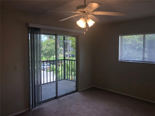 carpeted empty room with a ceiling fan, baseboards, and a textured ceiling