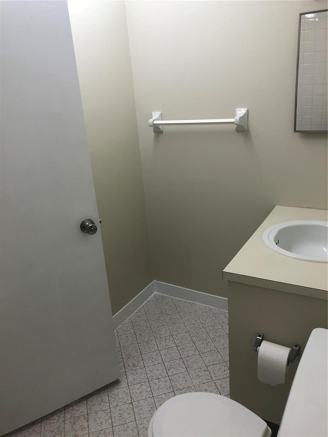 half bathroom with tile patterned flooring, vanity, toilet, and baseboards