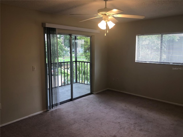 empty room with carpet floors, a textured ceiling, baseboards, and a ceiling fan