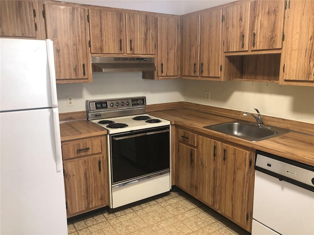 kitchen with brown cabinets, light floors, a sink, white appliances, and under cabinet range hood