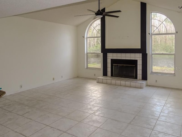 unfurnished living room featuring a tile fireplace, vaulted ceiling, and ceiling fan