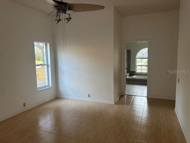 tiled spare room with plenty of natural light, baseboards, and ceiling fan