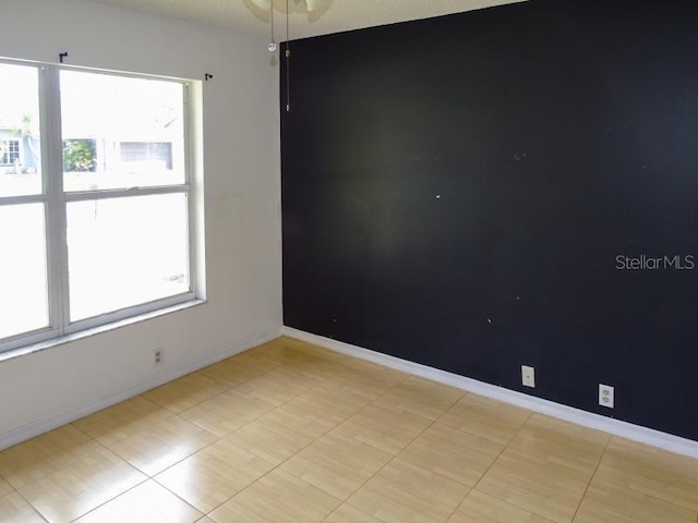 spare room with a wealth of natural light and baseboards