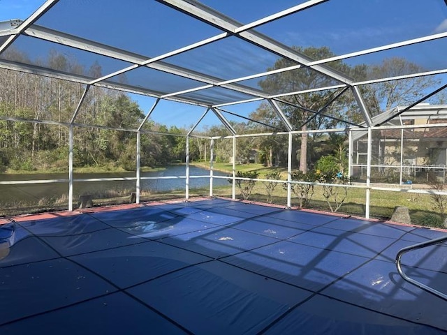 view of pool featuring glass enclosure and a water view