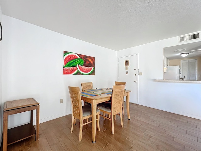 562 Orange Dr Unit 33, Altamonte Springs, FL 32701 - dining area featuring visible vents, a textured ceiling, baseboards, and wood finished floors