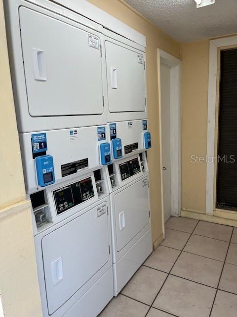 562 Orange Dr Unit 33, Altamonte Springs, FL 32701 - shared laundry area with a textured ceiling, stacked washer and clothes dryer, light tile patterned flooring, and washing machine and clothes dryer