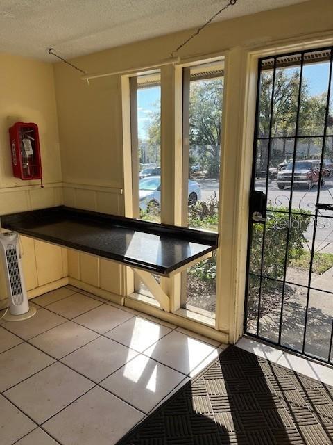 562 Orange Dr Unit 33, Altamonte Springs, FL 32701 - doorway to outside featuring a textured ceiling, light tile patterned flooring, and wainscoting