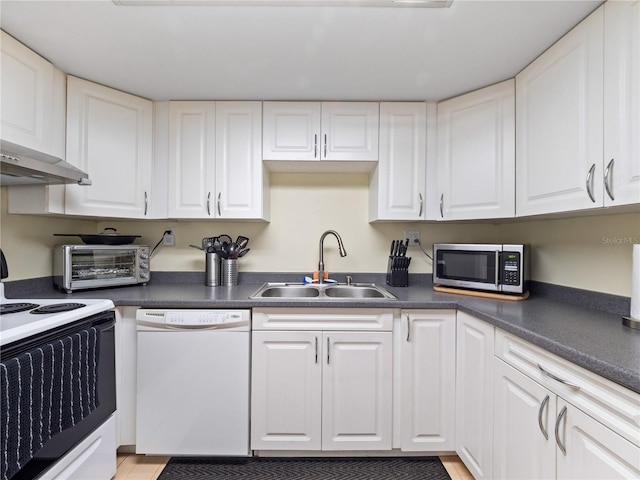 kitchen with dark countertops, white appliances, white cabinets, and a sink