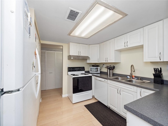 kitchen featuring dark countertops, visible vents, a sink, white appliances, and under cabinet range hood