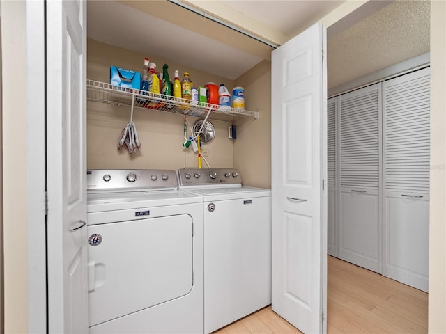 clothes washing area featuring laundry area, light wood finished floors, and washing machine and clothes dryer