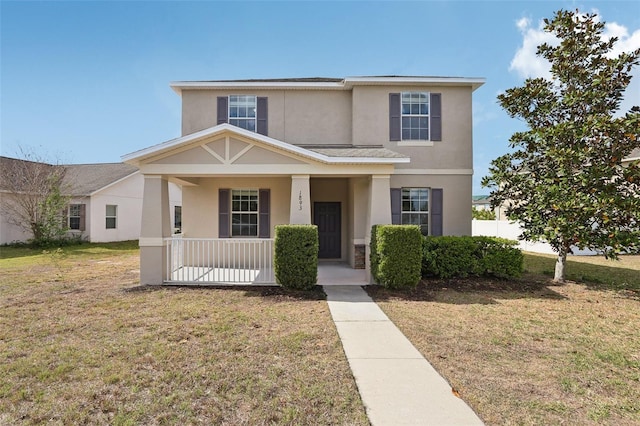 view of front of property with covered porch, a front lawn, and stucco siding