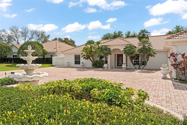 view of front of property with fence, a tiled roof, and stucco siding