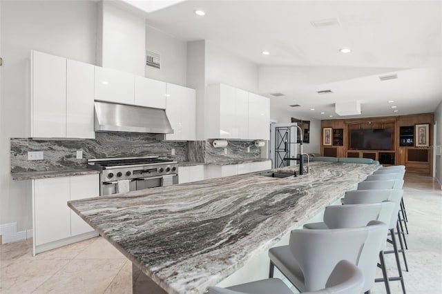 kitchen with stainless steel stove, white cabinets, a sink, a kitchen breakfast bar, and extractor fan