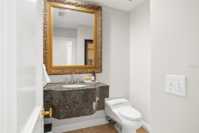 half bathroom with toilet, visible vents, baseboards, vanity, and tile patterned floors