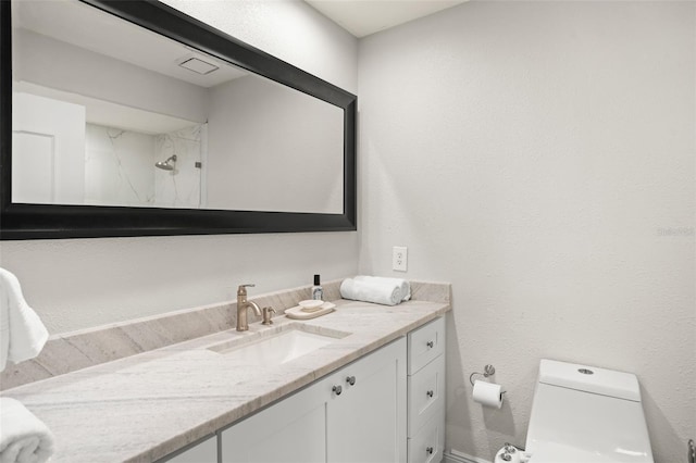 bathroom featuring toilet, a textured wall, a shower, and vanity