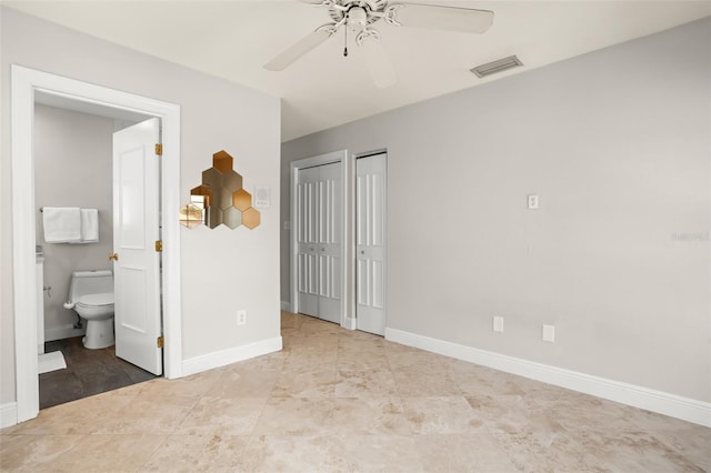 unfurnished bedroom featuring baseboards, visible vents, a ceiling fan, connected bathroom, and multiple closets