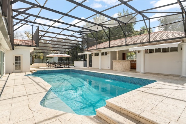 pool featuring exterior kitchen, glass enclosure, a patio, and outdoor dry bar