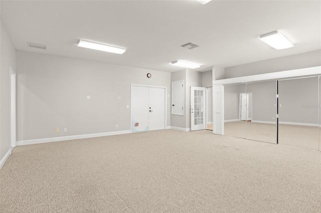 basement featuring visible vents, light carpet, and baseboards