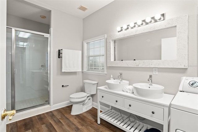 bathroom featuring visible vents, wood finished floors, a sink, and washer / dryer