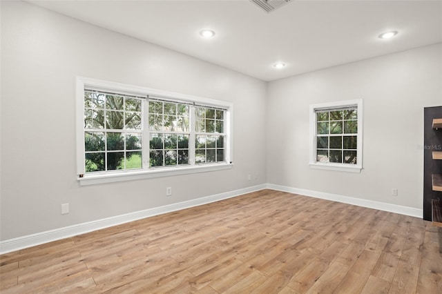 unfurnished room featuring visible vents, light wood finished floors, a wealth of natural light, and baseboards