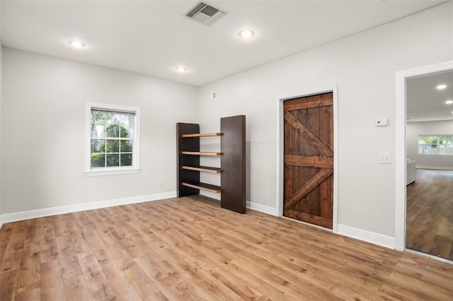 empty room with light wood-style floors, visible vents, and baseboards