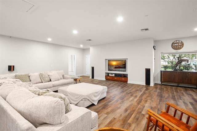 living area with recessed lighting, a baseboard heating unit, wood finished floors, visible vents, and baseboards