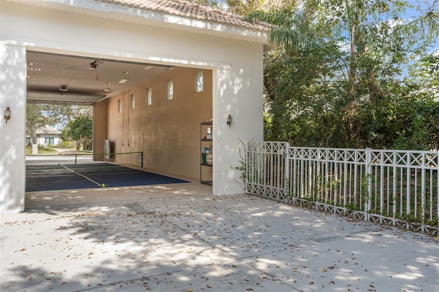 view of home's exterior featuring a garage, driveway, fence, and stucco siding