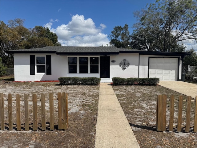 view of front of home featuring a fenced front yard, driveway, an attached garage, and stucco siding