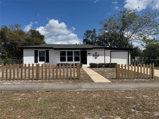 single story home with a garage, a fenced front yard, and stucco siding